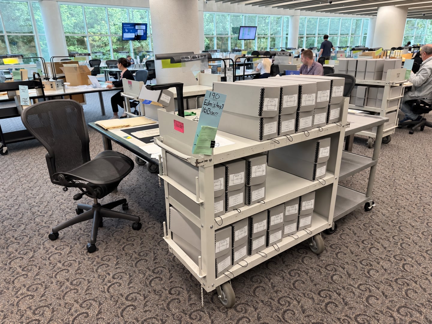 A cart stacked with grey archive boxes of 93rd Bomb Group records in the research room at the National Archives, College Park.